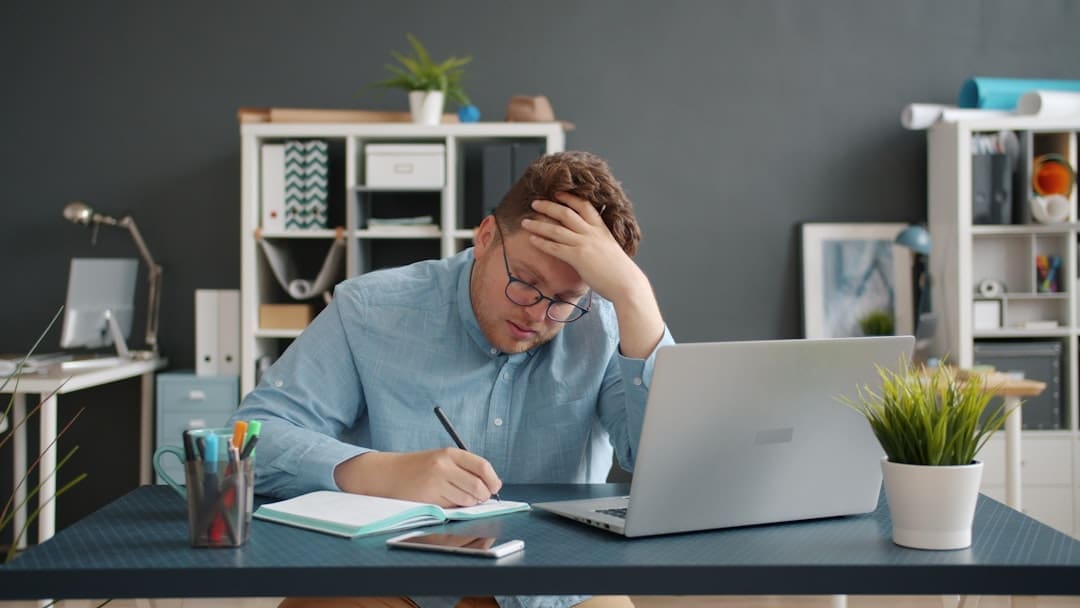 adult overwhelmed at desk with papers and laptop, mental fatigue